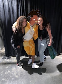 two women posing for a picture with a cartoon character